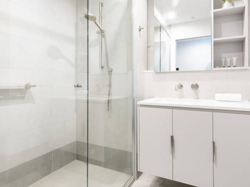 Sleek shower area with glass partition and contemporary fixtures.