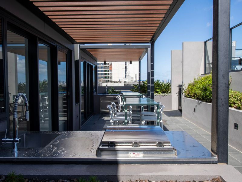 Covered rooftop BBQ area with modern grills and seating, great for outdoor dining and entertaining.