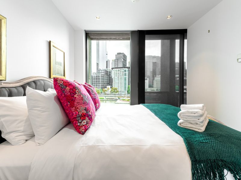 Master bedroom with plush bedding and balcony access