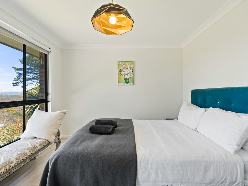 Sunlit bedroom with crisp linens and leafy window views