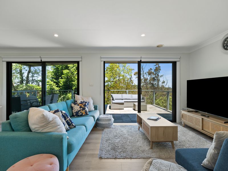Comfortable seating area with leafy views through large sliders