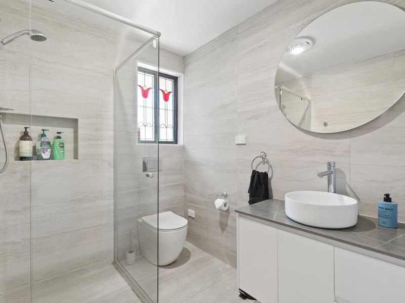 Stylish bathroom with walk-in shower, round vanity mirror, and modern finishes
