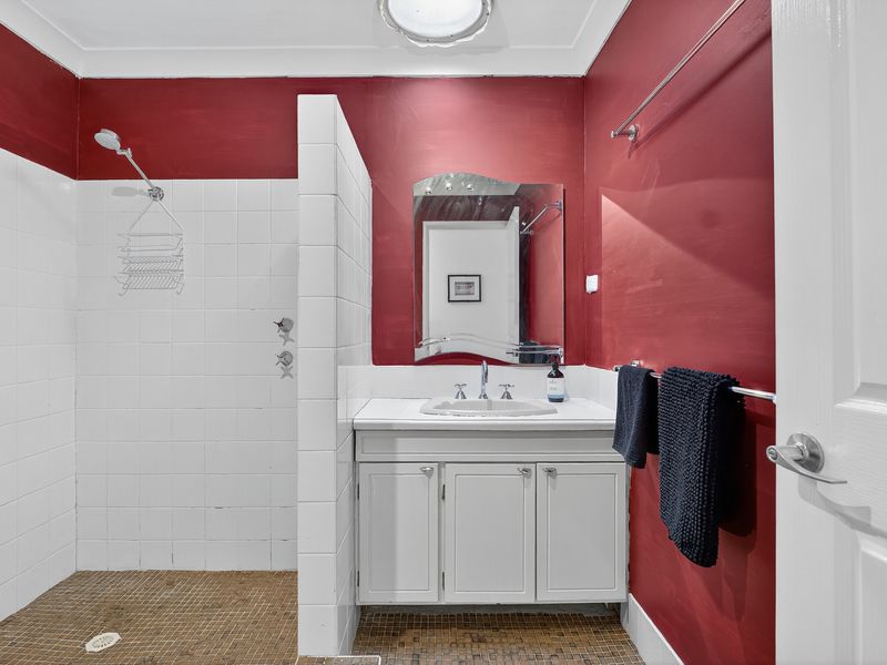 Bathroom with red feature walls, white vanity, and walk-in shower.
