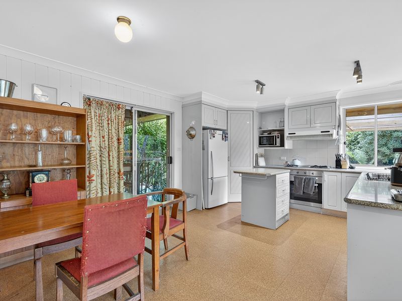 Warm dining area with timber cabinetry and leafy outlook.
