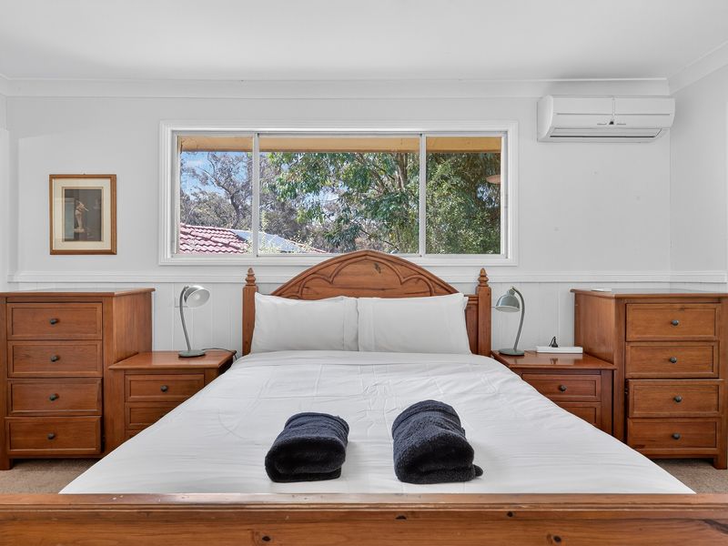 Spacious bedroom with wooden furniture and a neatly made bed.