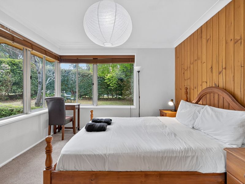 Bright master bedroom with large windows overlooking nature.
