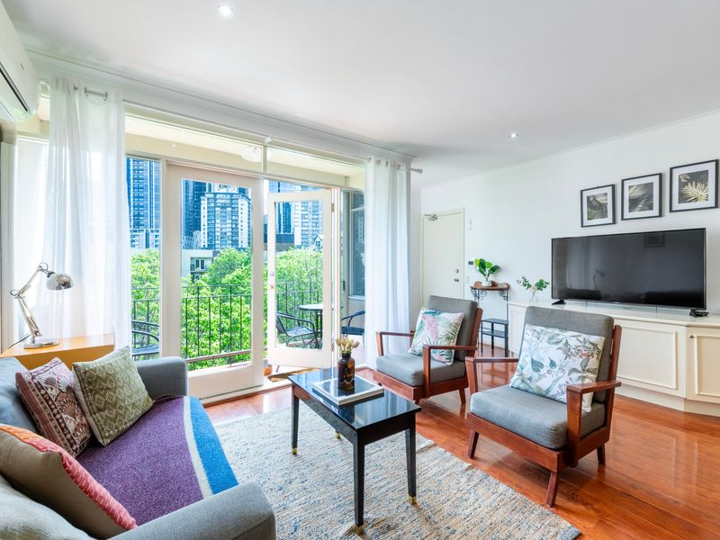 Bright, airy lounge area featuring large windows with a scenic city view, offering a cozy spot to unwind.