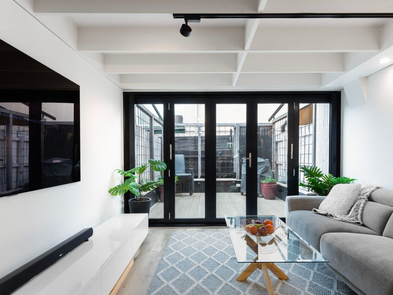 Bright living room with large TV and floor-to-ceiling doors.