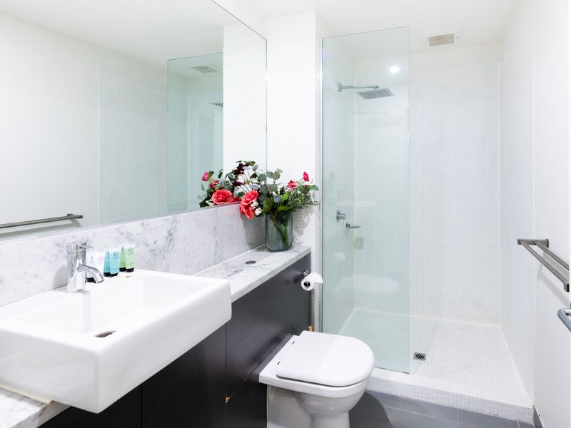 Crisp white design with marble-style finishes, glass shower, and premium fixtures.