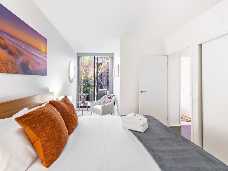 Another view of the same bedroom, highlighting outdoor greenery through wide windows.