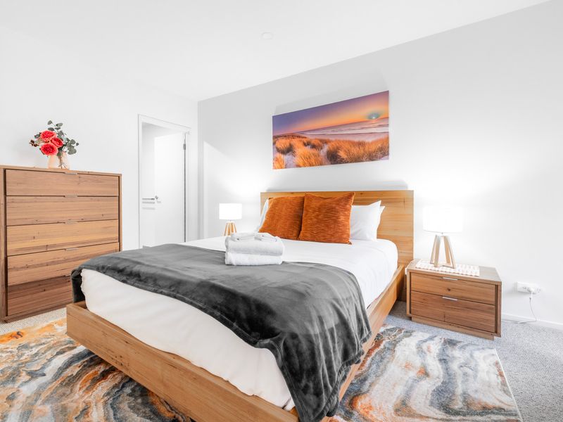 Queen bed with plush bedding, wooden furnishings, and calming neutral tones.