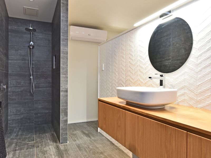 Walk-in shower with slate-style tiles and frameless glass.