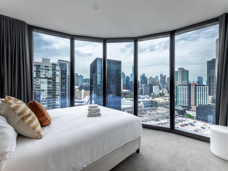 Bright bedroom with panoramic floor-to-ceiling city views.