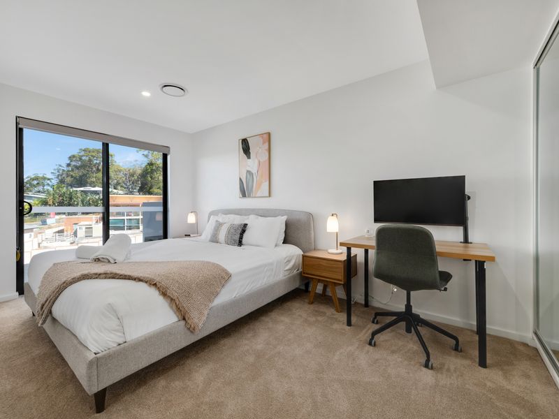 Sunlit bedroom with workspace and TV