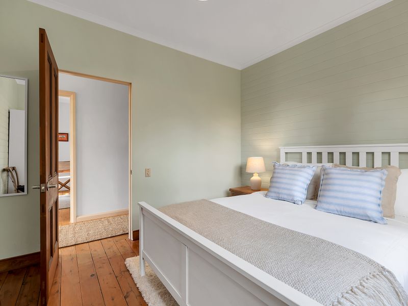 Well-lit bedroom with clean styling and timber flooring.
