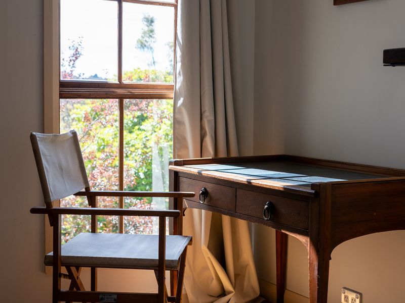 Cozy writing desk with natural light and forest outlook.