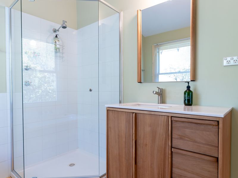 Fresh and modern bathroom with timber vanity and glass shower.