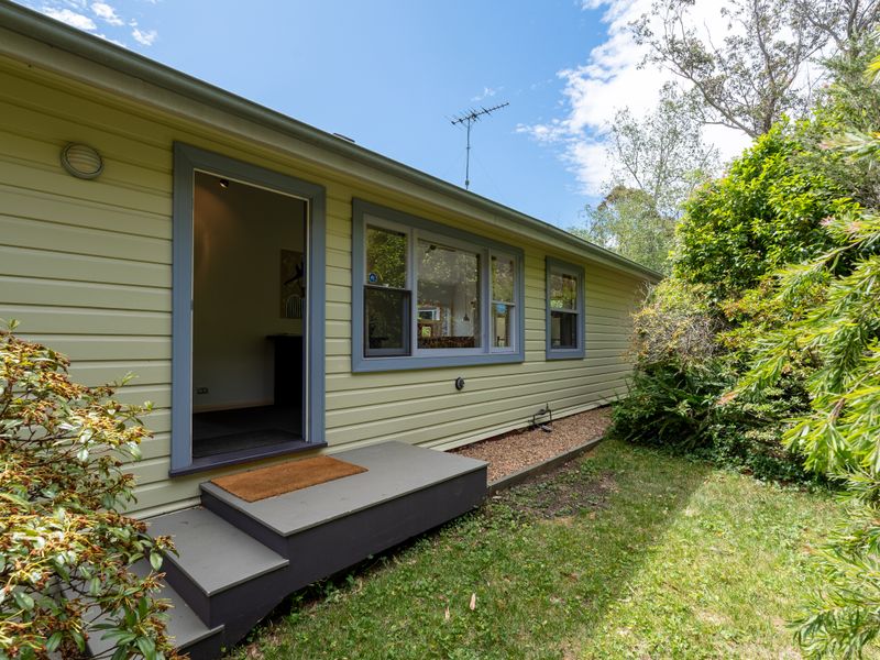 Charming exterior entrance framed by lush garden plants.