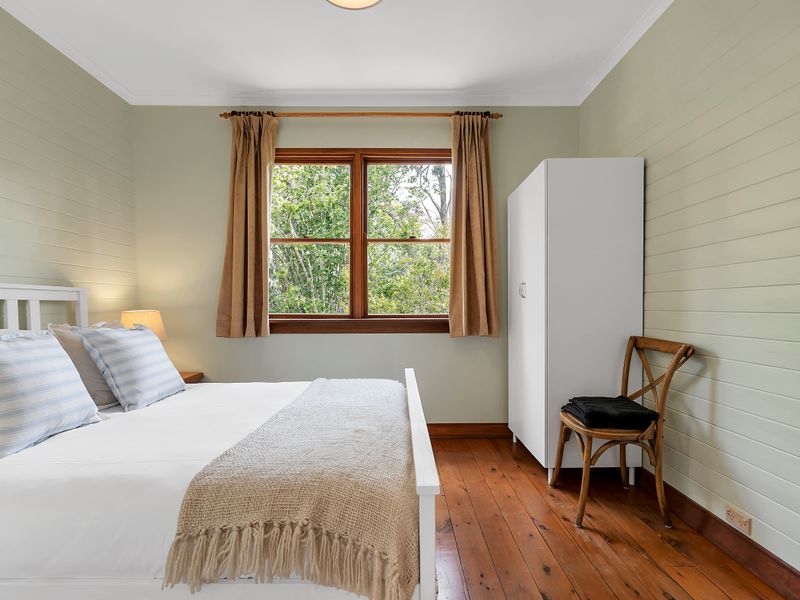 Bright bedroom with twin beds and a leafy garden outlook.
