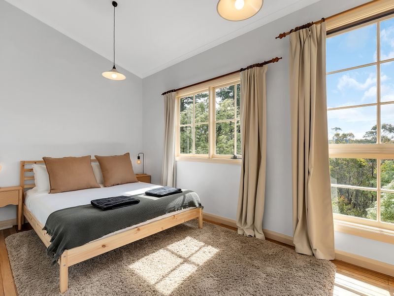 Bright bedroom with queen bed and large picture windows.