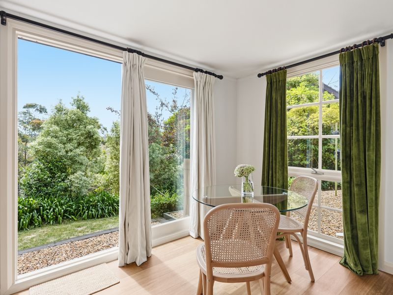 Sunny dining area framed by full-height glass doors and garden views.