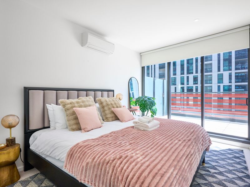 Cozy bedroom with a plush bed, soft textures, and large windows.