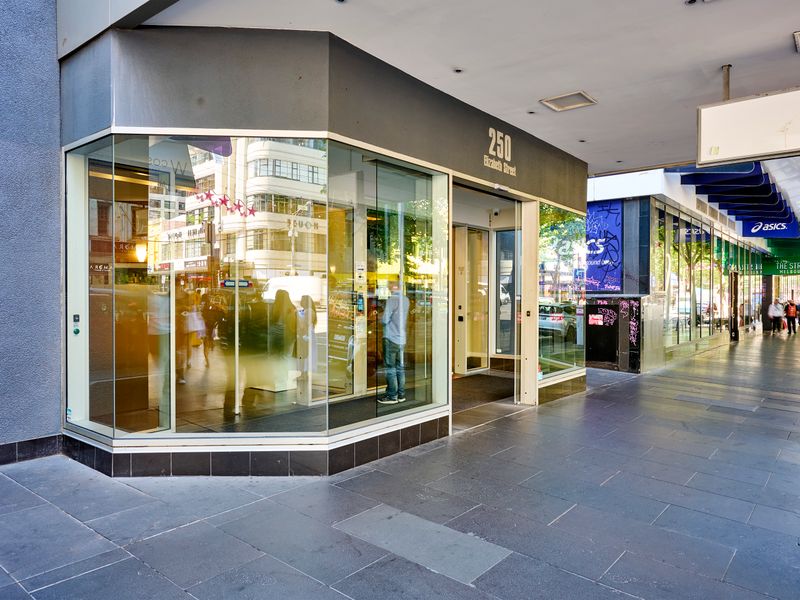 Street-level entrance with secure building access and nearby shops
