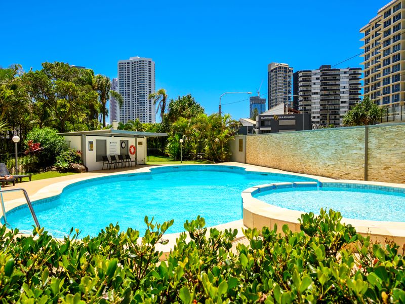 Sparkling outdoor pool surrounded by lush greenery and skyline views.
