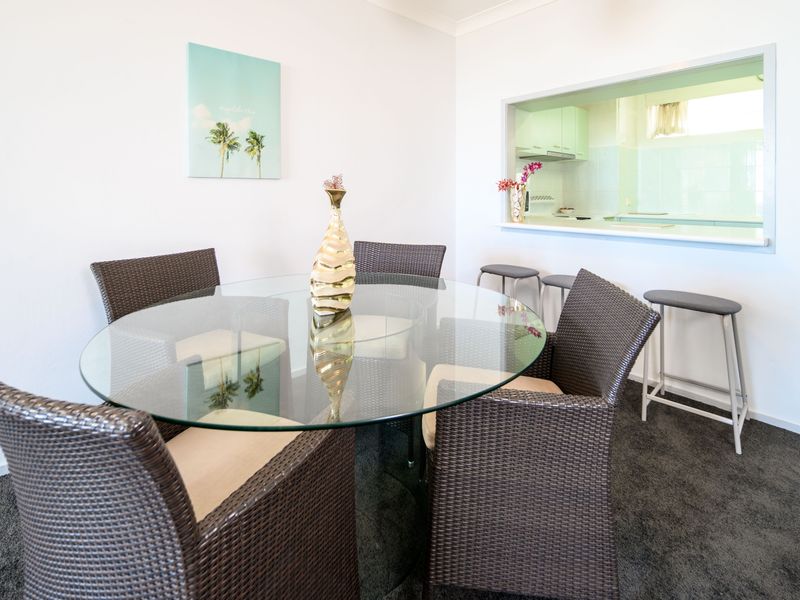 Dining nook with glass table and woven chairs.