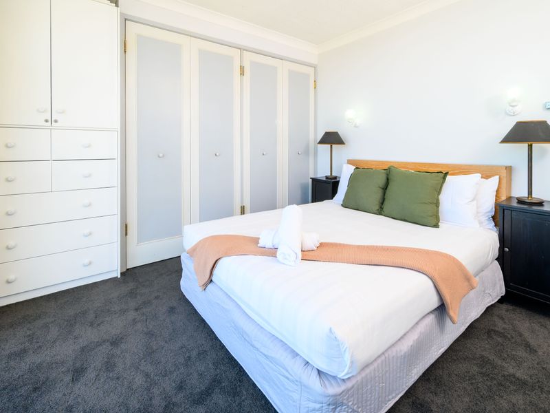 Serene bedroom with built-in wardrobes and soft bedding.