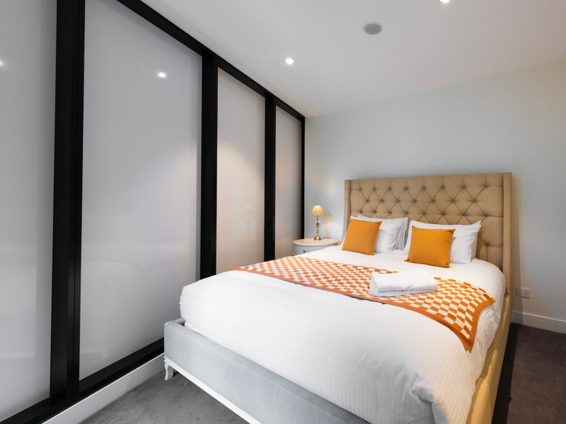 Sunlit bedroom styled with crisp linens and plush pillows.