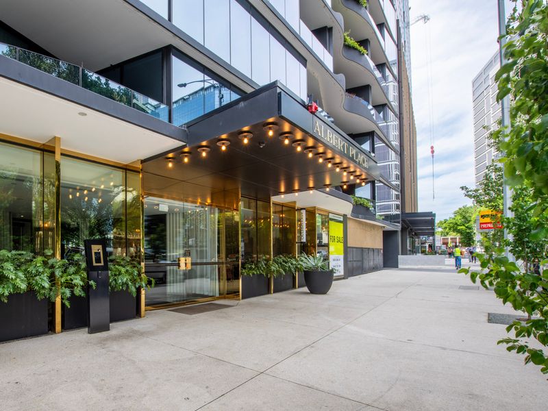 Welcoming building entrance framed by lush greenery.