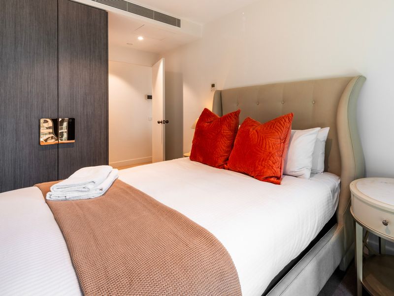 Cozy bedroom setup with warm accent cushions.