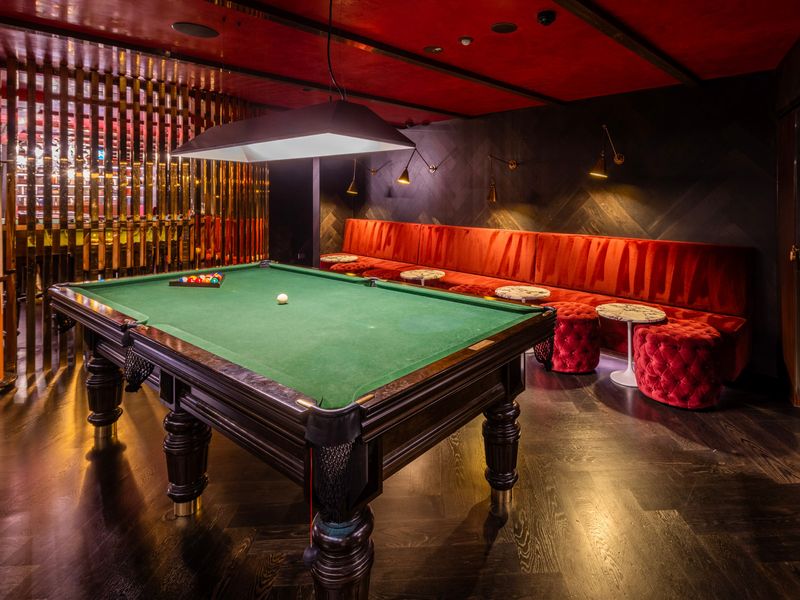 A moody, upscale billiards lounge with warm lighting