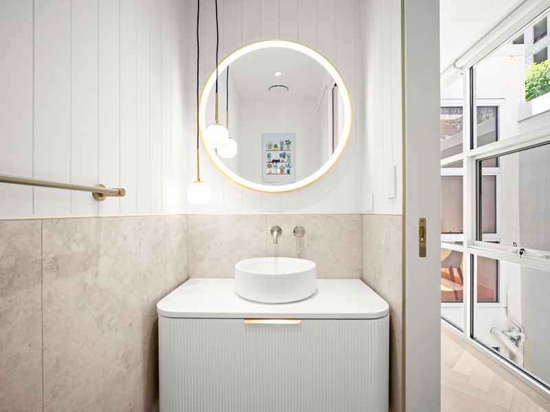 Bright powder room with designer mirror and contemporary basin