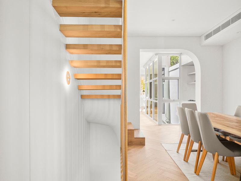 Light-filled hallway with staircase and dining area
