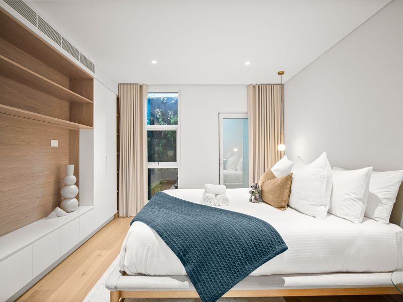 Primary bedroom featuring a plush king bed and warm wood accents
