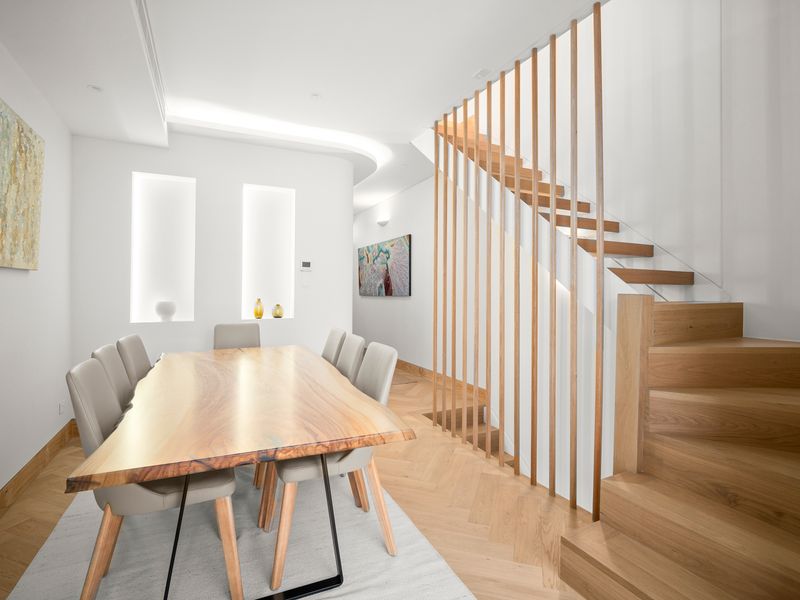 Stylish dining area with natural wood tones and open stairway