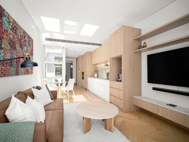 Open-plan living area with sofa, wall-mounted TV, and skylights