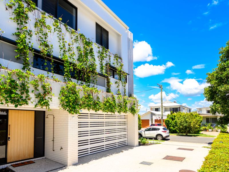 Modern building exterior with lush greenery and secure entry.