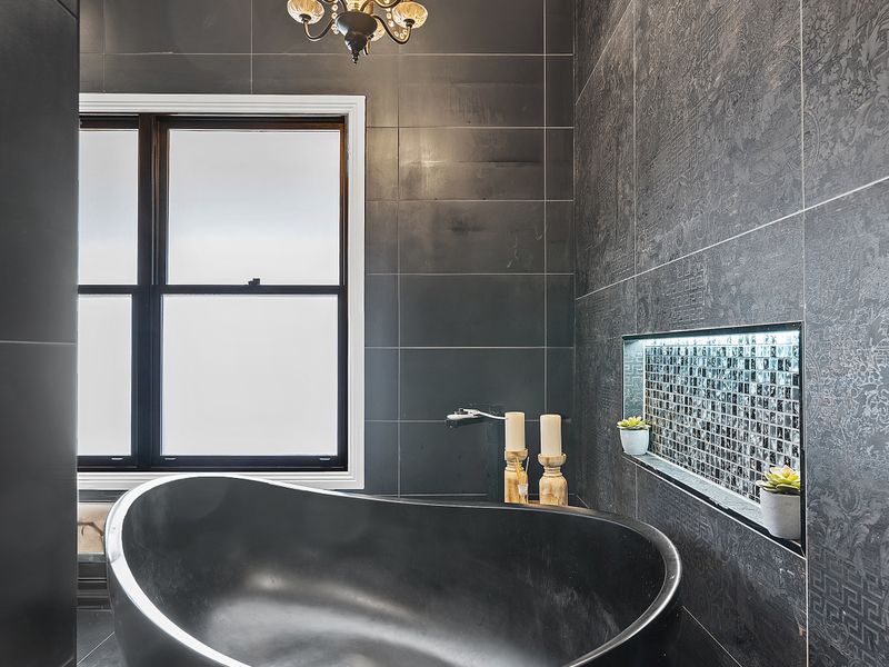 Elegant tub with dark feature tiles for a relaxing bath experience.