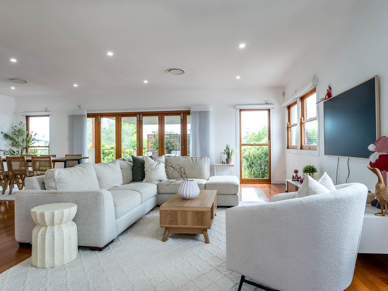 The layout perfectly balances a cozy media area with a large wall-mounted TV and a spacious dining zone for family gatherings.