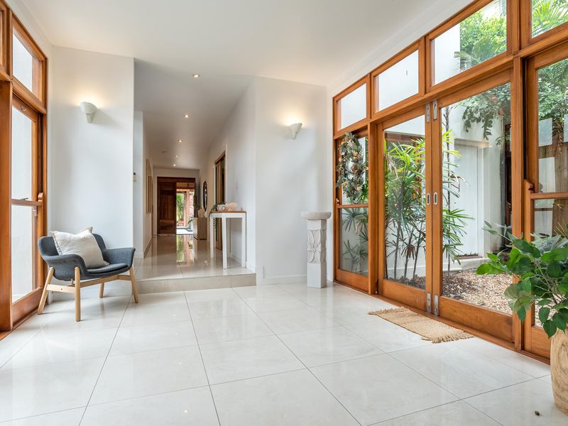 Make a grand entrance into this spectacular architectural home. The wide foyer features polished white tiles, soaring ceilings, and expansive timber-framed glass