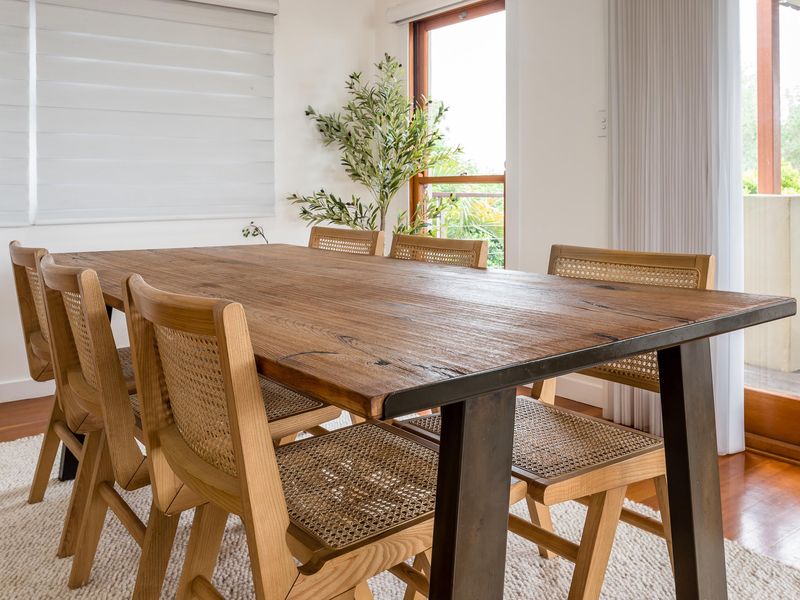 Host memorable dinners in this beautifully appointed dining area. Featuring a large, rustic timber dining table paired with stylish rattan-backed chairs, the space is elevated by a lush olive tree and direct access to the outdoor terrace.