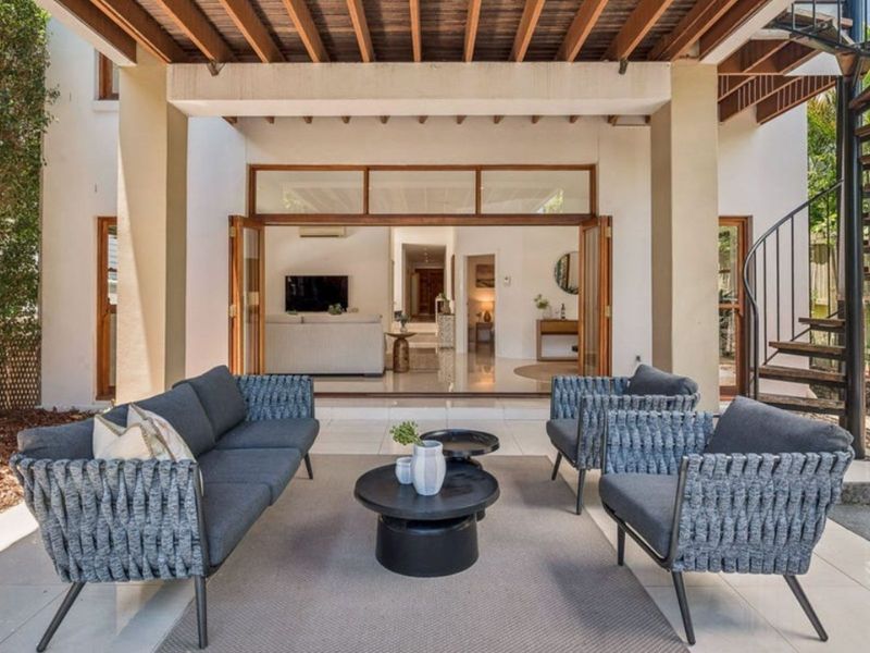 The space is styled with a dark grey outdoor sofa and matching armchairs featuring a woven texture.