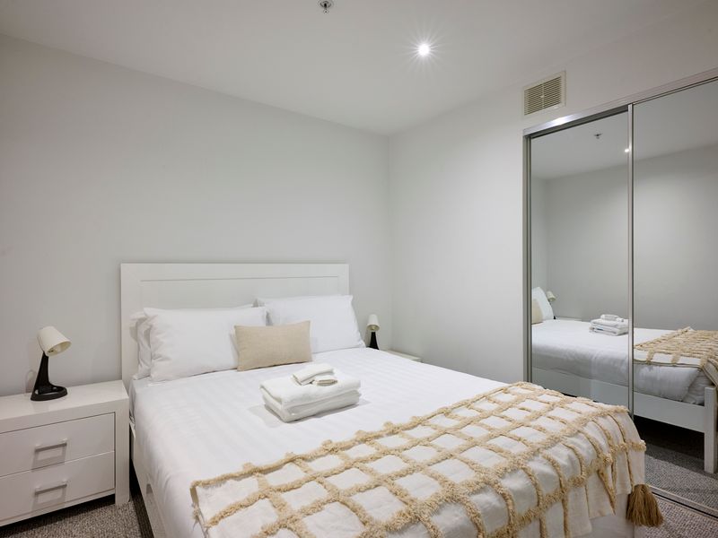 Bright bedroom with plush bedding and built-in wardrobes