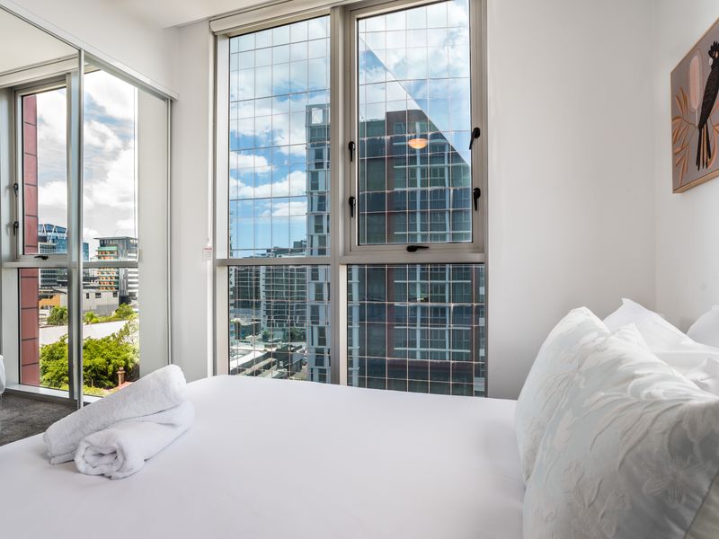 Sun-filled bedroom with large windows and city views