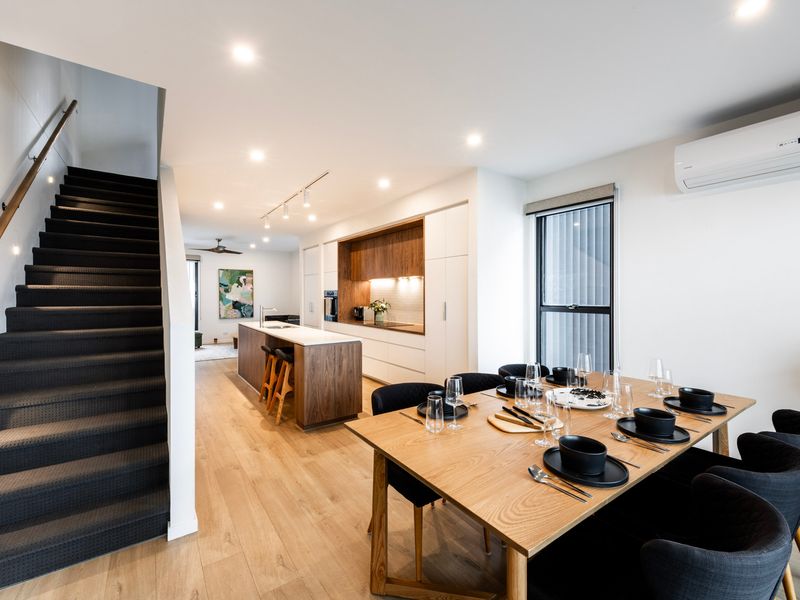 Dining space for gathering beside sleek black staircase feature.
