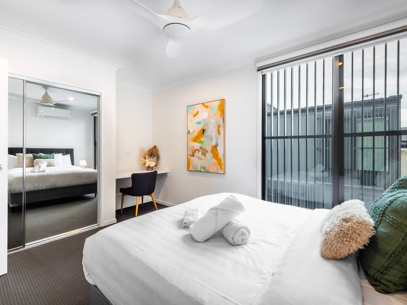 Spacious bedroom with mirrored wardrobe and soft, calming tones.