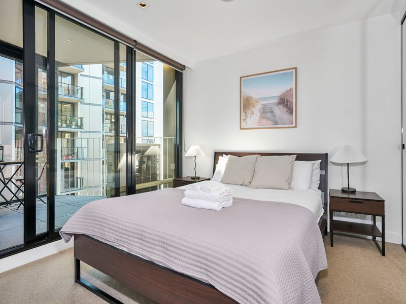 Comfortable queen bedroom with balcony access and natural light